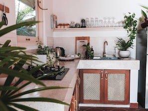 Una cocina con estufa a gas, armarios de madera, un lavamanos y diferentes utensilios.