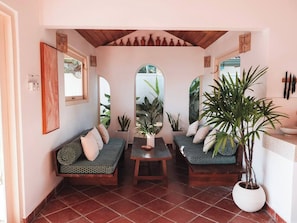 Una habitación acogedora con techo de madera, un conjunto de sofás, una mesa y plantas en macetas.