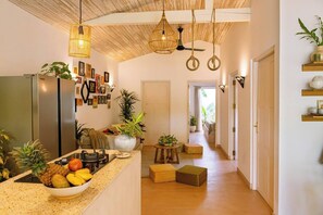 Una cucina moderna con un frigorifero, una ciotola di frutta e lampade a sospensione.
