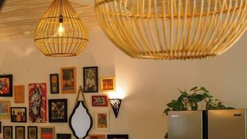 A room with a large mirror, a refrigerator, and various framed artworks on the wall.