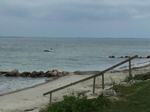 Ein Strand mit einer Holzbank, sandigem Ufer und einem Boot im Wasser.