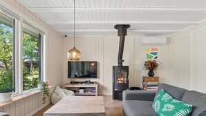 Ett mysigt vardagsrum med en öppen spis, en tv och en bekväm sittgrupp.