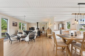 A spacious living area with a fireplace, wooden flooring, and a dining area with a table and chairs. - Spacious cottage close to Enebærodde (Otterup)