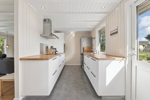 A modern kitchen with white cabinetry, wooden countertops, and a built-in stove. - Spacious cottage close to Enebærodde (Otterup)