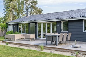 A modern house with a deck, outdoor furniture, and large windows. - Spacious cottage close to Enebærodde (Otterup)