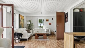 A modern living room with a white sofa, a wooden coffee table, and a wooden cabinet. - Lovely holiday home in Nykøbing Mors (Nykøbing M)