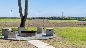 A park with a tree, concrete seating, and wind turbines in the background. - Lovely holiday home in Nykøbing Mors (Nykøbing M)