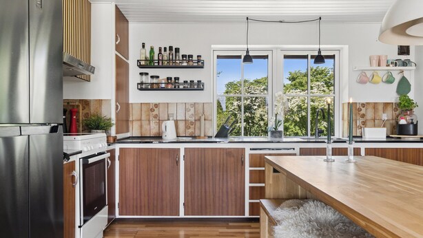 A modern kitchen with wooden cabinets, a stainless steel refrigerator, and a large window with a view of trees. - Lovely holiday home in Nykøbing Mors (Nykøbing M)