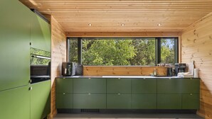 A modern kitchen with green cabinets, wooden ceiling, and a large window overlooking greenery. - Modern holiday home near Dueodde Beach (Nexø)