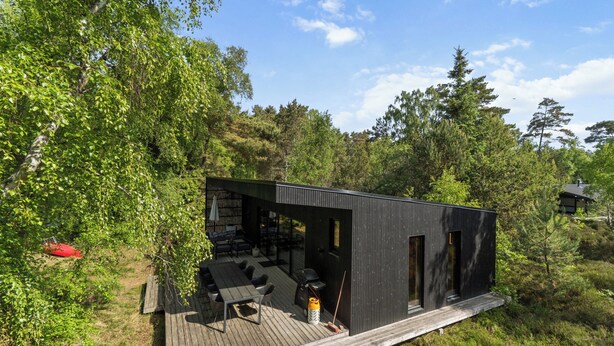 A modern cabin with a deck, outdoor seating, and a fire pit. - Modern holiday home near Dueodde Beach (Nexø)