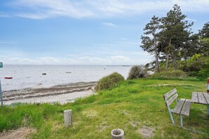En strand med en bænk, en træpæl og en fjern båd.
