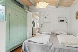 Une chambre avec deux lits, une armoire et un ventilateur de plafond.