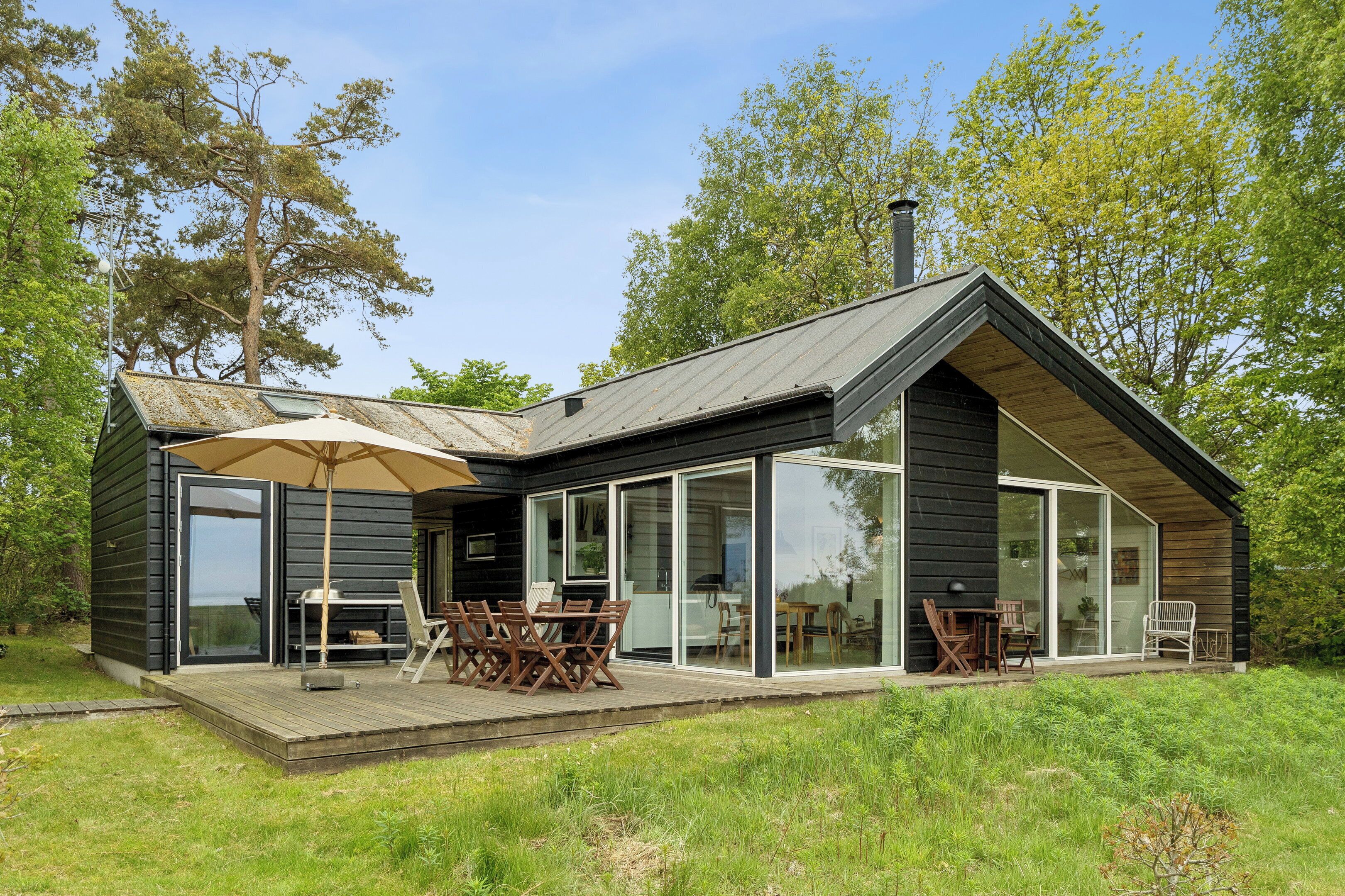 A modern cabin with a deck, glass sliding doors, and a dining area.