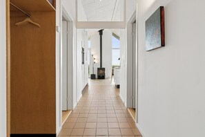 A hallway with a wooden closet, a fireplace, and a painting on the wall. - Cozy low-energy home with sea views (Ørsted)