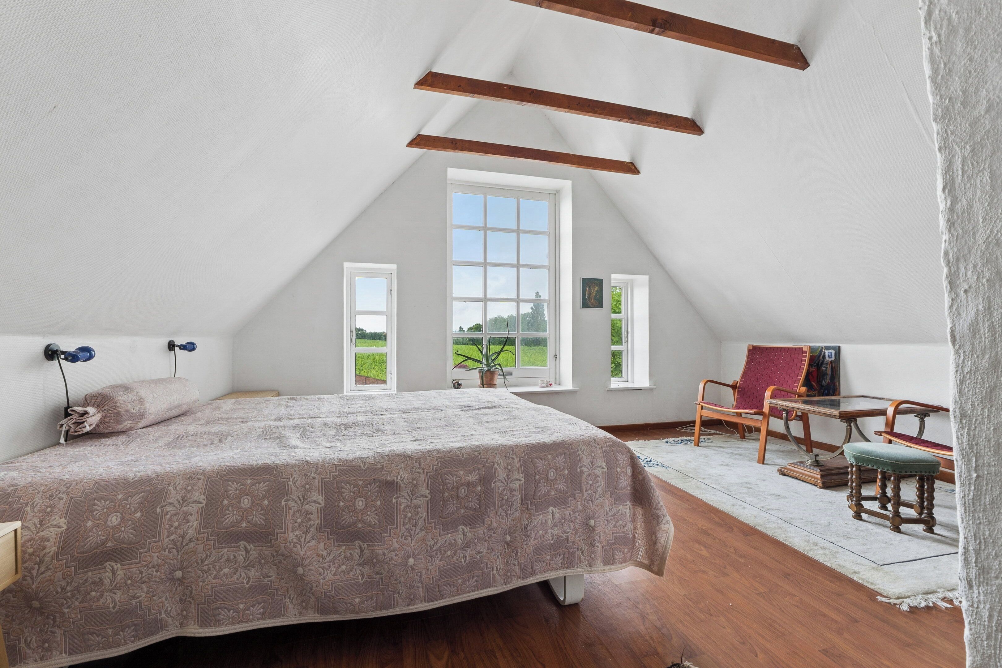 Une chambre avec un grand lit, une fenêtre, une chaise et une table.
