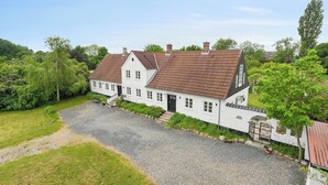A white house with a gravel driveway and a garden. - Large charming house for 12 guests (Snøde)