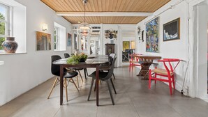 A dining area with a wooden ceiling, a round table with chairs, and artwork on the walls. - Large charming house for 12 guests (Snøde)