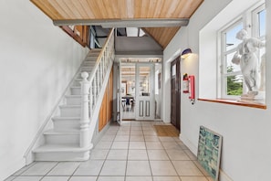 Eine Treppe mit weißen Balustraden, einer Holzboden und einem Fliesenboden, die zu einer Tür führt.
