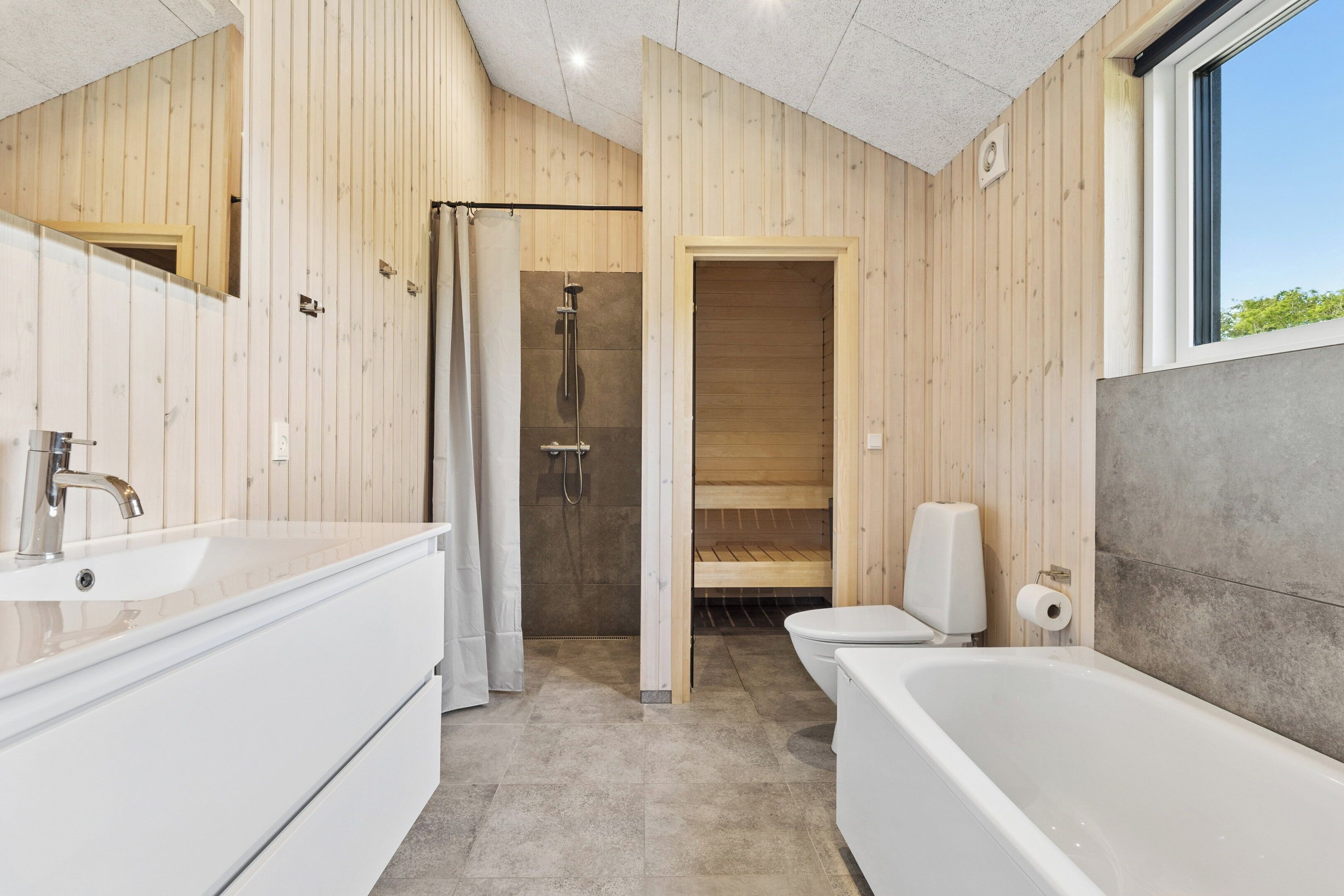 Une salle de bain moderne avec un intérieur en bois, une baignoire, une douche et des toilettes.