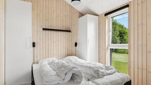 Une chambre à coucher avec un lit, une fenêtre et des murs en bois.