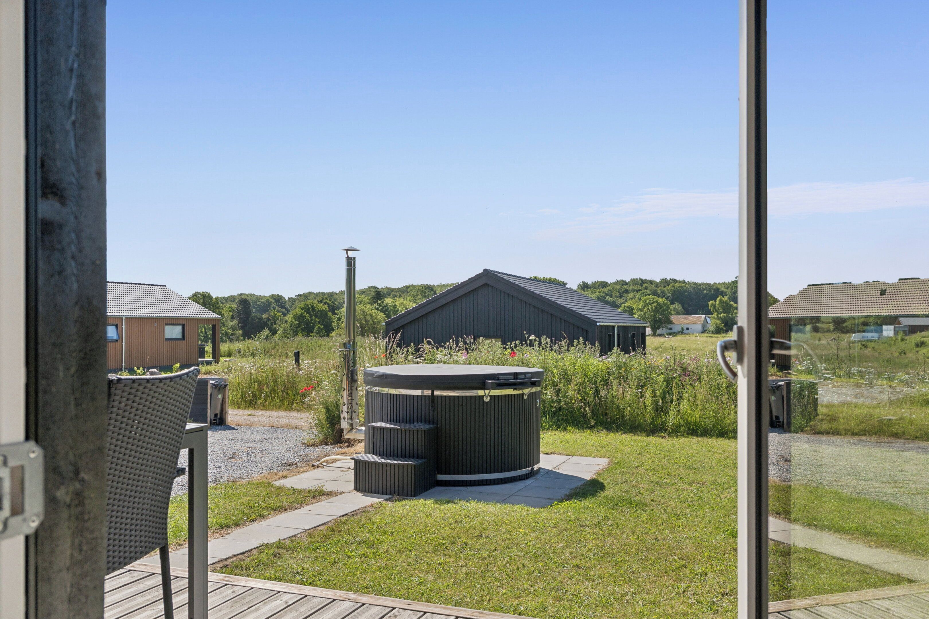 A residential area with a grassy yard, a wooden deck, and a large trash bin.