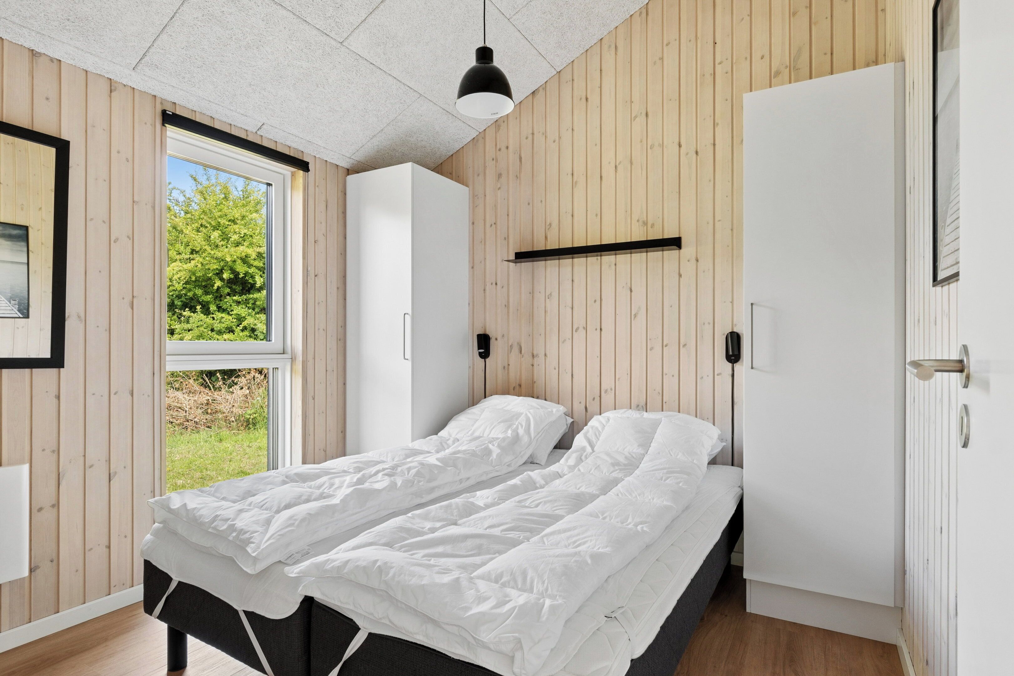 A bedroom with a bed, a wardrobe, a window, and a door.