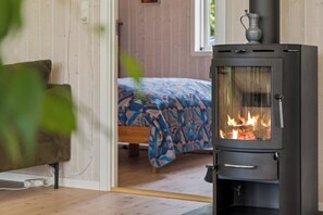 Ein Zimmer mit Bett, Sofa, einem schwarzen Kaminofen und einem Fenster.