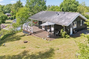 Eine Holzhütte mit einer Terrasse, Sitzgelegenheiten im Freien und einer Flagge.