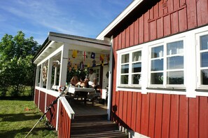 A red building with a porch and a table outside. - Cottage on the island IVÖ in Skåne (Fjälkinge)
