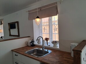 Eine Küche mit Spüle, einem Fenster mit Blick, einer Hängeleuchte und einem Spiegel an der Wand.
