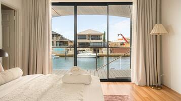 A bedroom with a large bed, a view of a marina, and a balcony with curtains.
