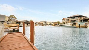 A wooden dock extending into calm water, surrounded by residential buildings with balconies and large windows. - Waterfront Halls Head Retreat – Sleeps 8, Spa & Home Theatre (Halls Head)