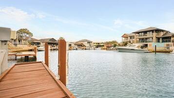 A wooden dock extending into calm water, surrounded by residential buildings with balconies and large windows.