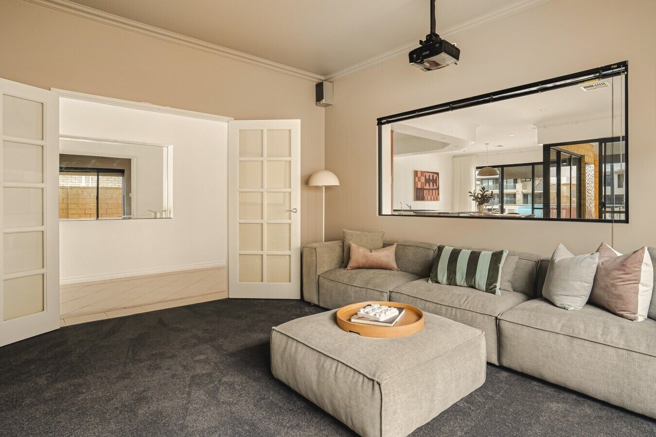 A living room with a sofa, ottoman, and a large mirror.