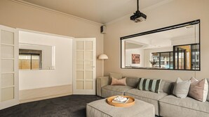 A living room with a sofa, ottoman, and a large mirror. - Waterfront Halls Head Retreat – Sleeps 8, Spa & Home Theatre (Halls Head)