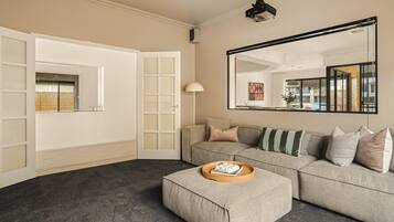 A living room with a sofa, ottoman, and a large mirror.