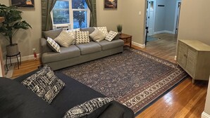 A living room with a sofa, a rug, a ceiling fan, and a window with curtains. - Terrific 5-bedroom charming house in older neighborhood in Salem (Salem)