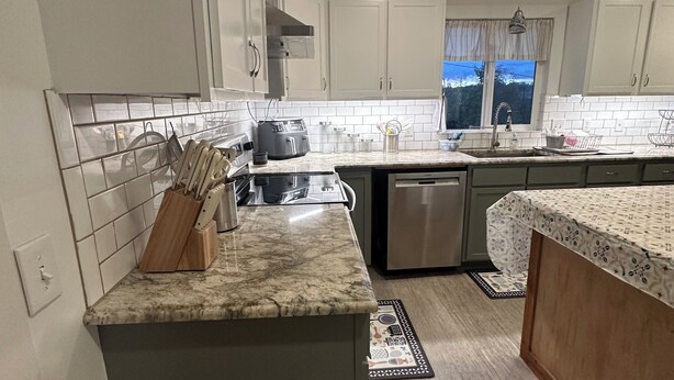 A modern kitchen with white cabinets, a granite countertop, and a built-in dishwasher. - Terrific 5-bedroom charming house in older neighborhood in Salem (Salem)