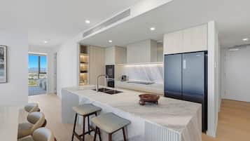 Una cocina moderna con una isla grande, electrodomésticos integrados y vistas al exterior.