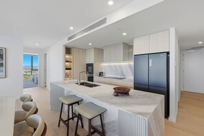 A modern kitchen with a large island, built-in appliances, and a view to the outside.