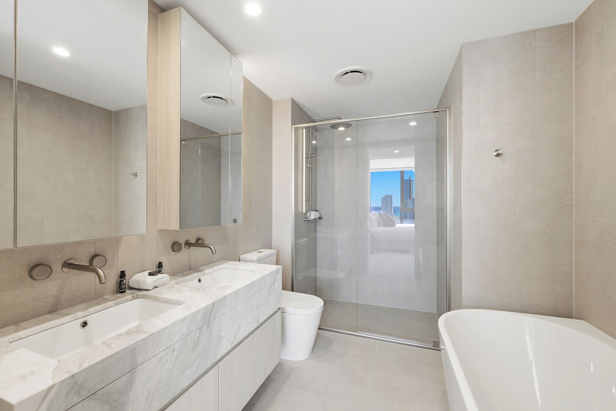 Un baño moderno con un espejo grande, cabina de ducha, bañera y retrete.