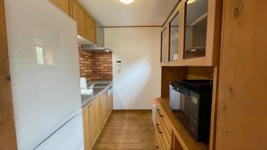 Una cocina estrecha con armarios de madera, un refrigerador blanco, lavavajillas y protector contra salpicaduras de ladrillo.