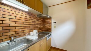 Uma cozinha com painel de parede em tijolo, pia de aço inoxidável, armários de madeira e micro-ondas embutido.
