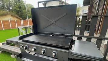 Ein Grill mit vier Kochfeldern, einem Seitentisch und einer Schutzhaube.