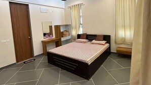 Un dormitorio con cama, ventilador de techo, mesita de noche, espejo y ventana con cortinas.
