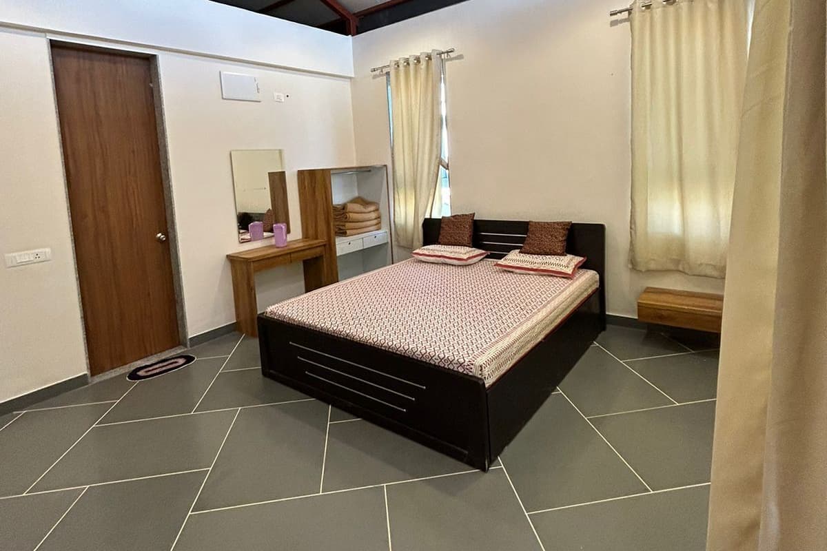 Un dormitorio con cama, ventilador de techo, mesita de noche, espejo y ventana con cortinas.