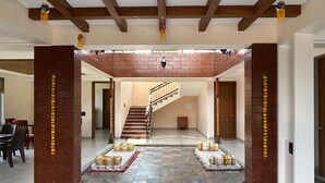 Un interior espacioso con una escalera central, suelo de piedra y vigas de madera en el techo.
