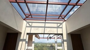 Un interior moderno con techo de vidrio, una escalera y vistas al exterior.