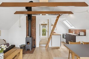 Ein Loft-Wohnbereich mit Küche, Kamin und einer Wendeltreppe zu einer erhöhten Ebene.