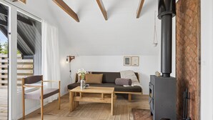 Ein Wohnzimmer mit einer Couch, einem Holztisch, einem Sessel, einem Kamin und Blick durch eine Schiebetür.